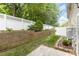 The backyard is bordered with a white fence and features a brick retaining wall and green grass at 121 Quality Dr, Mount Holly, NC 28120