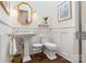 Elegant powder room features pedestal sink, hardwood floors, wainscoting, and stylish gold accents at 167 Quaker Rd, Mooresville, NC 28117
