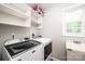 Well-lit laundry room featuring a modern washer and dryer, built-in shelving, and a utility sink at 2728 Touchstone Cir, Newton, NC 28658