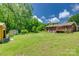Expansive green backyard featuring a red brick house with a wooden deck surrounded by mature trees at 286 Southside Rd, Rock Hill, SC 29730
