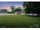 Expansive backyard with lush grass and white fence, enhanced by a vibrant sunset backdrop, virtually staged at 3807 Sweetgrass Ln, Charlotte, NC 28226