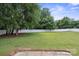 Green backyard enclosed by a white fence surrounded by mature trees, offering privacy and space at 3807 Sweetgrass Ln, Charlotte, NC 28226