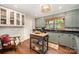 Well-lit kitchen showcasing green cabinets, black countertops, central island, and hardwood floors at 418 Melody Ln, Shelby, NC 28152