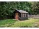 Charming backyard shed with wooden door and frame, nestled amongst mature trees and landscaping at 418 Melody Ln, Shelby, NC 28152