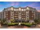 Elegant brick building with lush landscaping, fountain, and balconies against a colorful twilight sky at 4620 Piedmont Row Dr # 308, Charlotte, NC 28210
