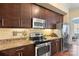 Modern kitchen with dark wood cabinetry, granite countertops, and stainless steel appliances at 4620 Piedmont Row Dr # 308, Charlotte, NC 28210