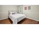 Cozy bedroom featuring a bed with white comforter, pillows and hardwood floors with neutral colored walls at 5016 Celeste Ct, Charlotte, NC 28270