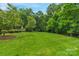 Lush backyard with manicured lawn surrounded by mature trees and landscaping at 5044 Dockside Ct, Matthews, NC 28104