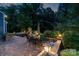 Inviting stone patio with outdoor fireplace, dining area, lounge seating, and beautiful landscape lighting at 5044 Dockside Ct, Matthews, NC 28104
