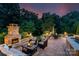 Relaxing brick patio featuring an outdoor fireplace, comfortable seating, dining table, and lush landscaping at 5044 Dockside Ct, Matthews, NC 28104