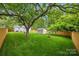 The backyard has a lush lawn, large shade tree, storage shed, fire pit, and wooden fence at 605 Cobb St, Lowell, NC 28098