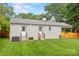 A spacious backyard featuring green grass and a gray home with two doors and a wooden fence at 605 Cobb St, Lowell, NC 28098