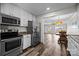 Open kitchen featuring stainless steel appliances and white cabinetry that seamlessly connects to the living and dining areas at 6518 Point Comfort Ln, Charlotte, NC 28226