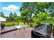 View of a beautiful wood deck with a table, barbecue, and lovely view of the spacious yard with mature trees at 6821 Millingden Ct, Charlotte, NC 28277