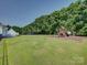 Large backyard with playground, mature trees, and a lush lawn, offering a private outdoor space at 736 Creekbridge Dr, Rock Hill, SC 29732