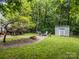 Backyard featuring fire pit, chairs, a small storage building, and lush surrounding greenery at 7830 Sarah Dr, Denver, NC 28037