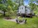 Well-manicured backyard with a fire pit, chairs, landscaped elements, a deck and lush greenery at 7830 Sarah Dr, Denver, NC 28037