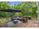Outdoor deck with patio furniture, umbrella, a chiminea, string lights, grill, and wooded background at 7830 Sarah Dr, Denver, NC 28037