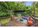 Outdoor deck with patio furniture, umbrella, a chiminea, string lights and a beautiful wooded background at 7830 Sarah Dr, Denver, NC 28037