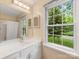 Bright bathroom with a large mirror and sink, complemented by natural light from a window at 8201 Lansford Rd, Charlotte, NC 28277
