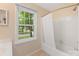 Well-lit bathroom featuring a tub and shower, complemented by a window offering a private backyard view at 8201 Lansford Rd, Charlotte, NC 28277
