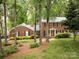 Traditional brick home with a manicured lawn and mature trees, offering shade and curb appeal at 8201 Lansford Rd, Charlotte, NC 28277