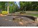 Backyard featuring a stone fire pit, patio, and retaining wall at 9219 Whispering Wind Dr, Charlotte, NC 28277