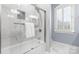 Bathroom bathtub with glass shower doors and white marble surround at 9219 Whispering Wind Dr, Charlotte, NC 28277