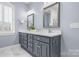 Bathroom with dual sinks, grey cabinets, white countertop, and white-framed mirrors at 9219 Whispering Wind Dr, Charlotte, NC 28277