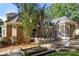 Exterior view of brick home featuring a screen porch, deck, and fire pit area at 9219 Whispering Wind Dr, Charlotte, NC 28277