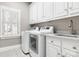 Laundry room with white cabinetry, modern appliances, and a utility sink at 9219 Whispering Wind Dr, Charlotte, NC 28277