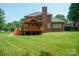 Expansive backyard with lush green grass and a charming brick home with a large wooden deck at 100 Woodwinds Dr, Mount Holly, NC 28120