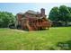 Lush green backyard featuring a charming brick home with a spacious wooden deck for outdoor living at 100 Woodwinds Dr, Mount Holly, NC 28120