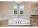 Corner soaking tub nook with travertine tile surround, bright windows, and neutral walls at 100 Woodwinds Dr, Mount Holly, NC 28120