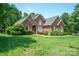 Charming red brick home featuring manicured lawn, mature trees, and a welcoming facade at 100 Woodwinds Dr, Mount Holly, NC 28120