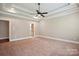 Spacious main bedroom featuring tray ceiling, ceiling fan, neutral walls, carpet, and entryway to en-suite bathroom at 100 Woodwinds Dr, Mount Holly, NC 28120