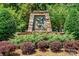 Stone community entrance sign surrounded by lush greenery and colorful bushes at 10300 Sweetleaf Pl, Charlotte, NC 28278