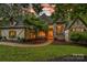 Charming front exterior with stone accents, lush landscaping, and a welcoming arched entryway at dusk at 10300 Sweetleaf Pl, Charlotte, NC 28278