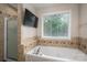 Bathroom featuring a tub with a window, a shower and a wall-mounted TV for comfortable bathing at 107 Ingonish Dr, Gastonia, NC 28056