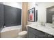 Elegant bathroom featuring gray tile, a shower-tub combo, and a sleek vanity at 11024 Shreveport Dr, Huntersville, NC 28078