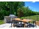 Outdoor kitchen and dining area with a stainless steel grill and lush green surroundings at 11024 Shreveport Dr, Huntersville, NC 28078