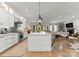 Open-concept kitchen with white cabinetry, large island, stainless appliances, and hardwood floors flowing into living area at 1160 S Kings Dr, Charlotte, NC 28207