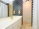 This bathroom has a white vanity, gold fixtures, and unique black and white patterned wallpaper at 1209 S South St, Gastonia, NC 28052