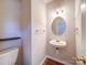 Stylish half-bathroom with a modern sink, round mirror, wood-look floors, and neutral wall paint at 12231 Stratfield Place Cir, Pineville, NC 28134