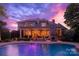 A luxurious backyard with a serene pool, covered patio, and brick fireplace against a dramatic evening sky at 1509 Churchill Downs Dr, Waxhaw, NC 28173