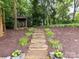 Landscaped backyard with stone steps leading to a shed, surrounded by greenery and mulch at 1638 Wensley Dr, Charlotte, NC 28210