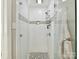 Shower with white subway tile and a grey accent stripe and designer tile on shower floor at 1638 Wensley Dr, Charlotte, NC 28210