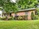 Traditional brick home with well-maintained landscaping, green lawn, and mature trees at 1638 Wensley Dr, Charlotte, NC 28210