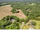 An aerial view shows the property with mature trees, open fields and lush, green landscaping at 2320 Doster Rd, Monroe, NC 28112