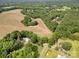 Aerial view shows the property with mature trees, open fields, a pool, and green landscaping at 2320 Doster Rd, Monroe, NC 28112